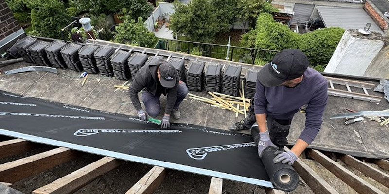 Application d’un rouleau d’isolation sur une toiture.
