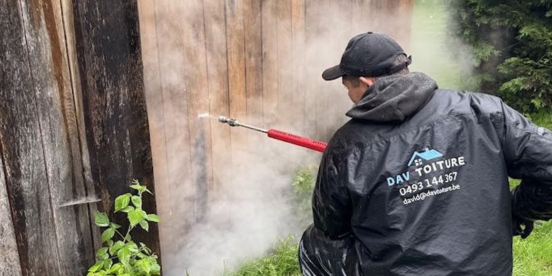 un ouvrier nettoie un bardage en bois avec un nettoyeur basse pression vapeur