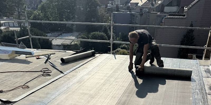 un ouvrier sur une toiture plate coupe du Derbigum pour préparer la pose 