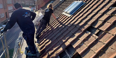 deux ouvriers inspectent une toiture avant le démontage