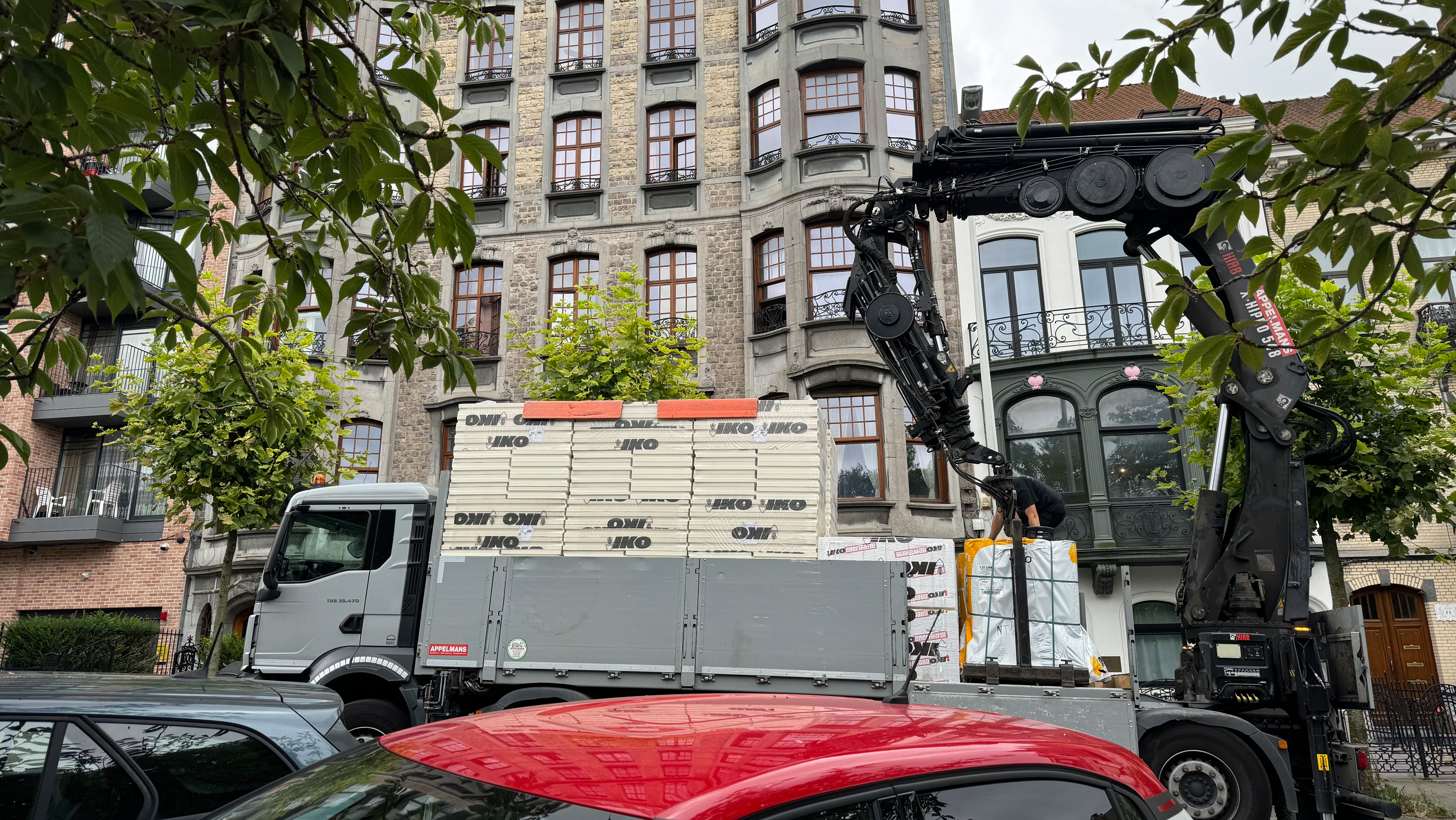 Camion grue qui livre sa cargaison d'isolation devant le chantier